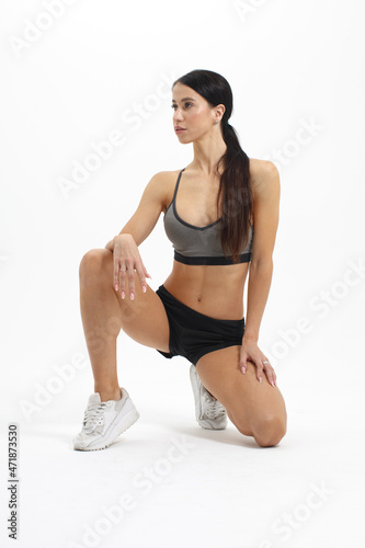 young wellness athletic woman in sportswear standing on knee cut out on white background