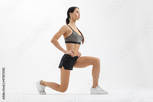 athletic sportswoman doing lunge exercise isolated on white background photo