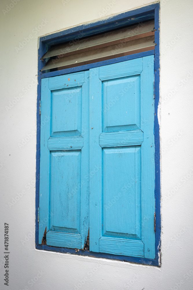 Pastel colorful blue wooden window frame on cement white wall wite space area. Building exterior design and object photo.