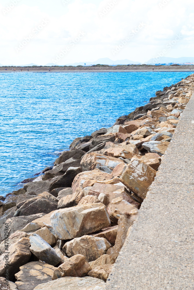 Concrete dam with defense rocks from the waves of the sea on a sunny day Concrete dam with defense rocks from the waves of the sea on a sunny day