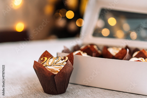 Celebratory cupcake in brown wrapper in front of white cardboard box © Anastassiya 