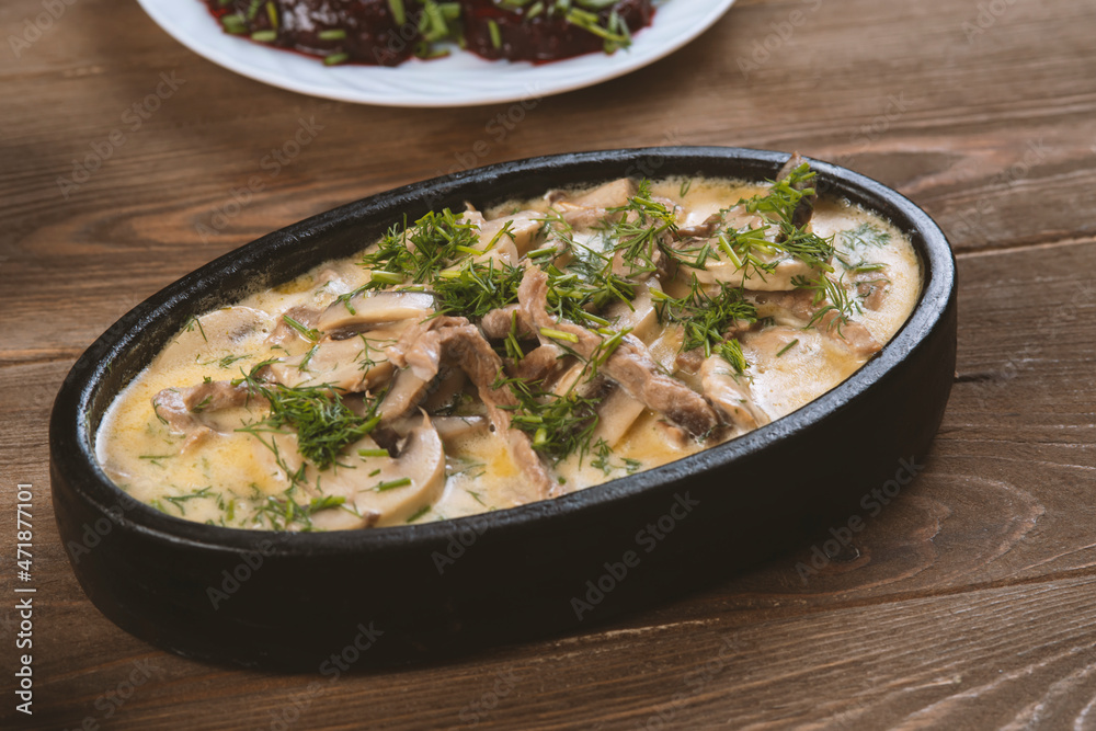 a dish made of pieces of beef, mushroom in cream sauce on dark wood