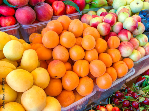 Apricots, nectarines, peaches, cherries in plastic containers at the market. Neatly folded fresh fruit. Proper nutrition. Healthy food