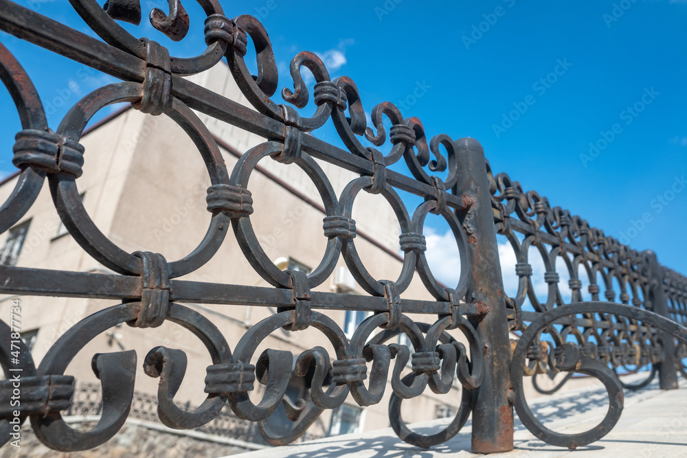 Metal forged railings. Background with beautiful urban geometry. Shiny steel fence.