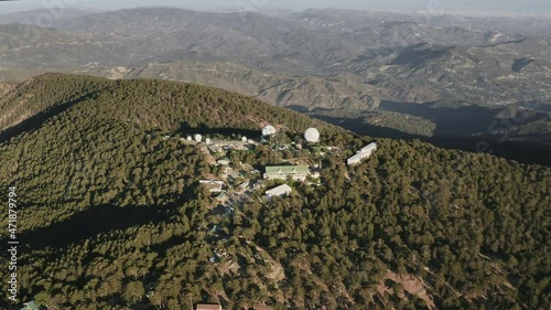 Hidden military science station in high mountain. Aerial view of meteorological radar observatory on mountain range surrounded pine tree forest. Science, climatology, weather forecasting. Astronomy