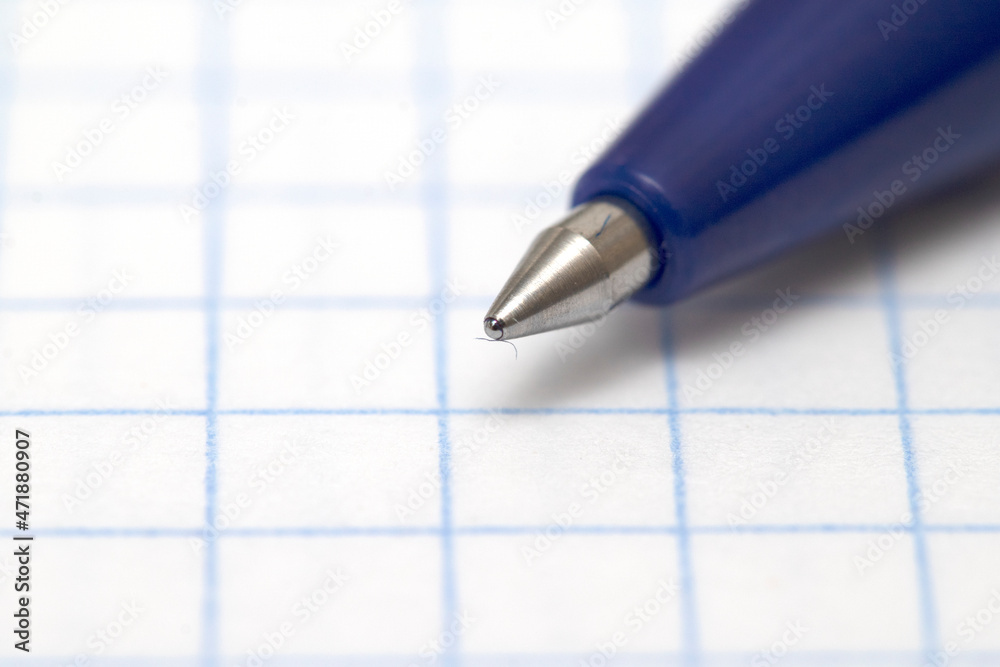 Close-up of a ballpoint pen on a checkered notebook. Close-up of a ballpoint pen on a checkered notebook.