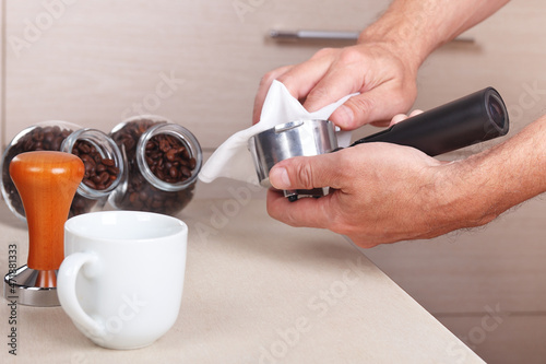 Barista wipes holder before making coffee above table.