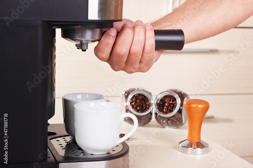 Barista inserts holder into coffee machine to make espresso.