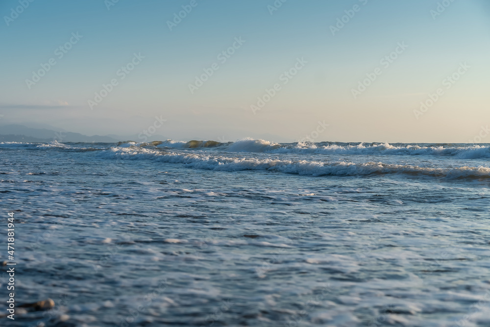 Waves roll onto the beach shore at sea before sunset. Beautiful nature photo. Waves roll onto the beach shore at sea before sunset. Beautiful nature photo.