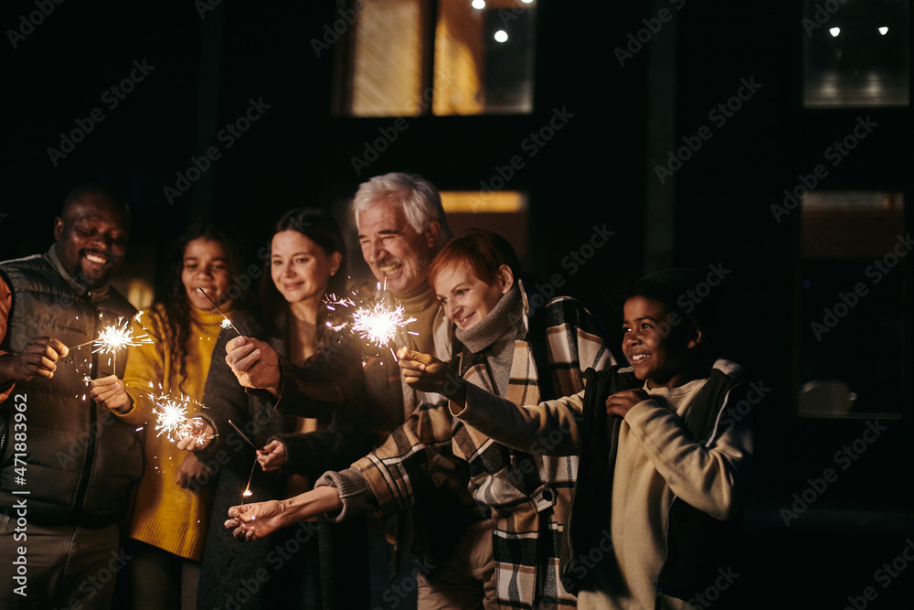 Large happy interracial family of three generations holding sparkling bengal lights while celebrating new year or xmas together Large happy interracial family of three generations holding sparkling bengal lights while celebrating new year or xmas together