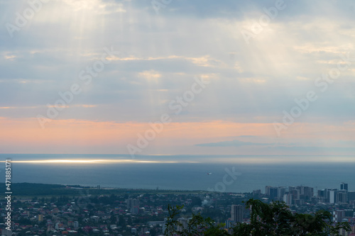 View from the mountains to Batumi  the rays of the sun shining into the sea  a plane flying away. Beautiful  fascinating view of the city of Batumi