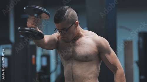 Muscular arab man training with dumbbells in the gym.