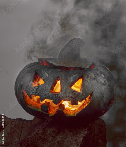 Halloween. A pumpkin on the background of a pond, it glows, a fiery flame burns inside it. The concept of the holiday of the night of all saints and scary dark fairy tales in the autumn harvest season