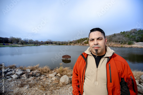 Adventure man hiking and walking in the walking in the woods and lake enjoying the fresh air while wearing an orange jacket and blue jeans. © Carlos Morales