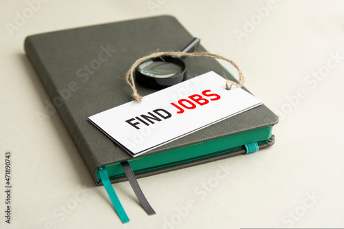 white card with text Find Jobs lies on a gray notebook. defocusing