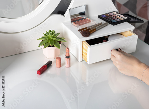 Obraz na plátne woman opens a drawer of white dressing table with products for make-up