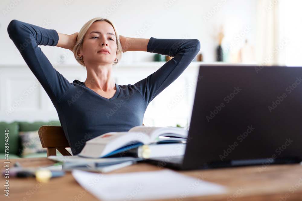 Woman looking at laptop. University student studying with books and laptop at home. Woman looking at laptop. University student studying with books and laptop at home.