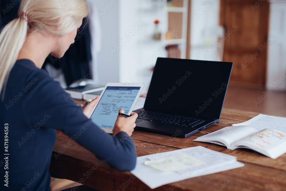 Woman studying at home. Female student reading notes on tablet Woman studying at home. Female student reading notes on tablet