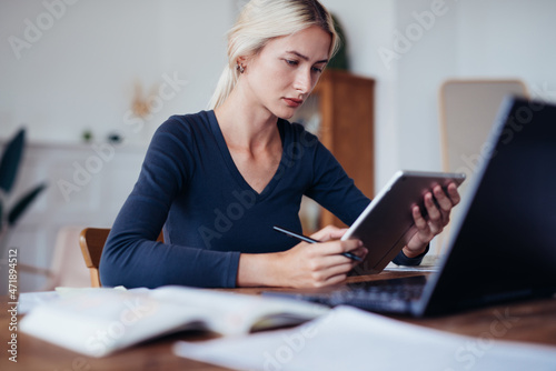 Female student at home studying at table with tablet