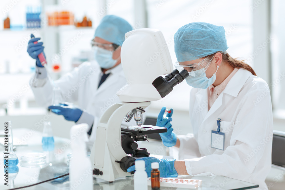 female scientist sitting in front of a microscope.