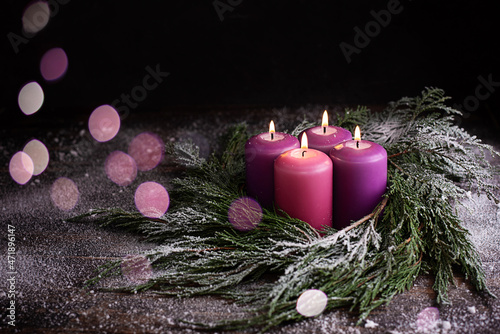 Christmas eve, wreath with four burning purple advent candles.