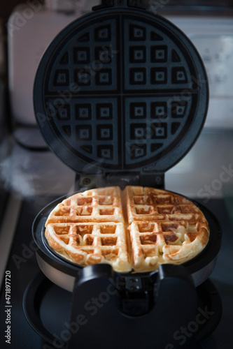 Steamy golden homemade waffle baking in waffle iron