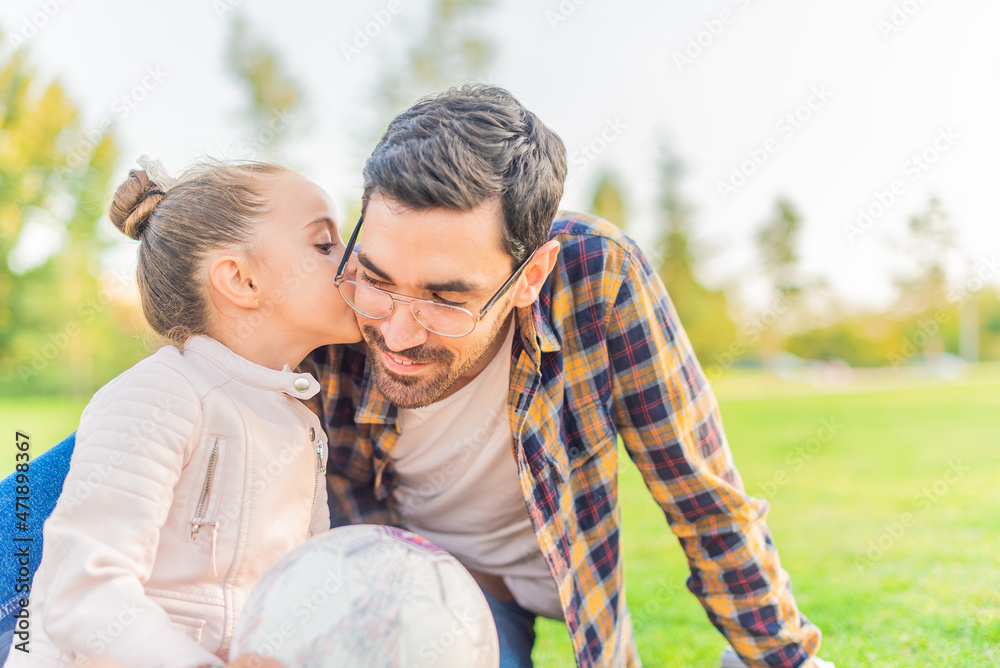 Fototapeta premium cute little girl kissing her single father in a park