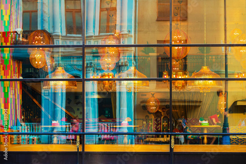 Bright background on showcases, windows of restaurant in national style with blurred reflections of city, outside view