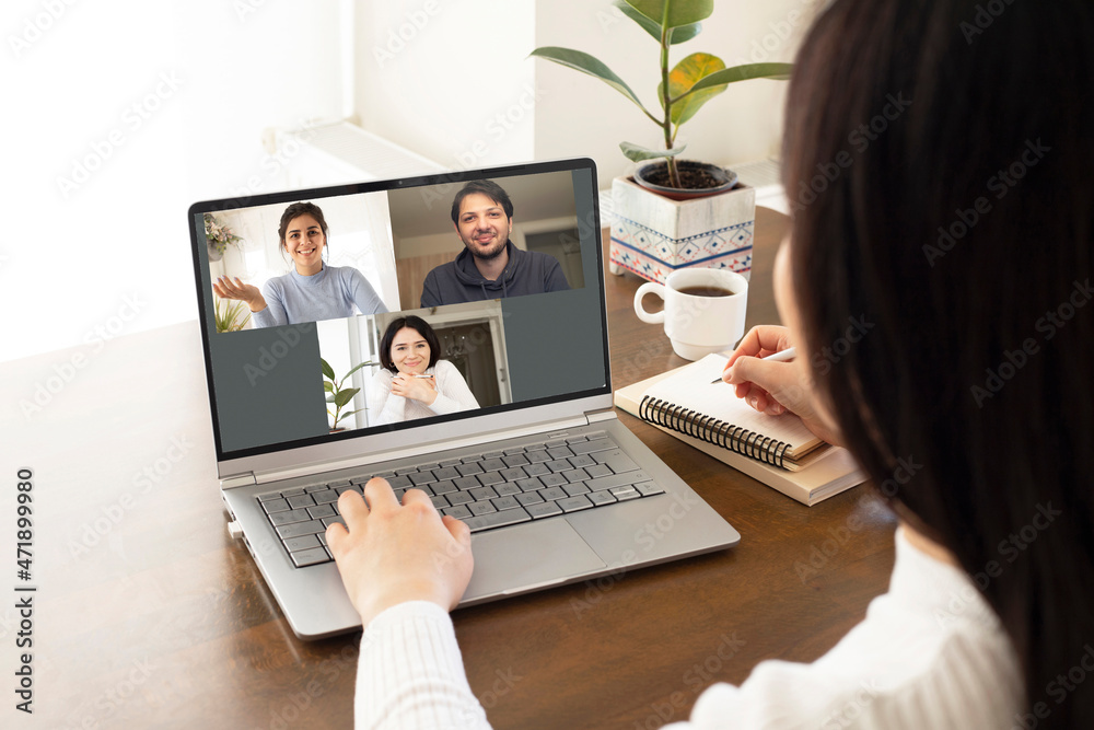 Woman sit at desk looking at computer screen where collage of diverse people webcam view. Videoconference at home office Woman sit at desk looking at computer screen where collage of diverse people webcam view. Videoconference at home office