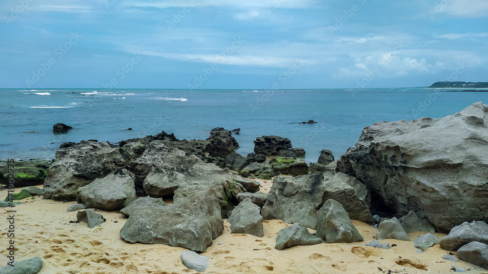 Linda vista de praia com muitas pedras e um céu azul