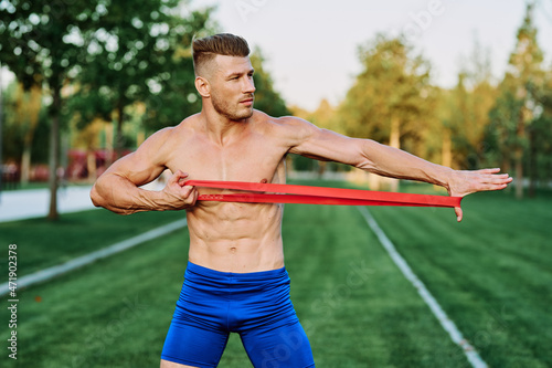 athletic man with a pumped up body in the park exercise fitness
