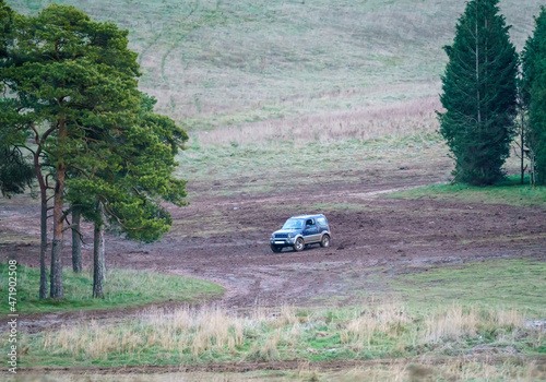 blue and silver Suzuki Jimny 4x4 off-road vehicle driven around a muddy expanse in woodland, Wiltshire UK photo