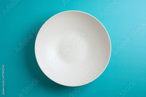Top down minimalist view of a white bowl on yellow background. White round plate on blue background