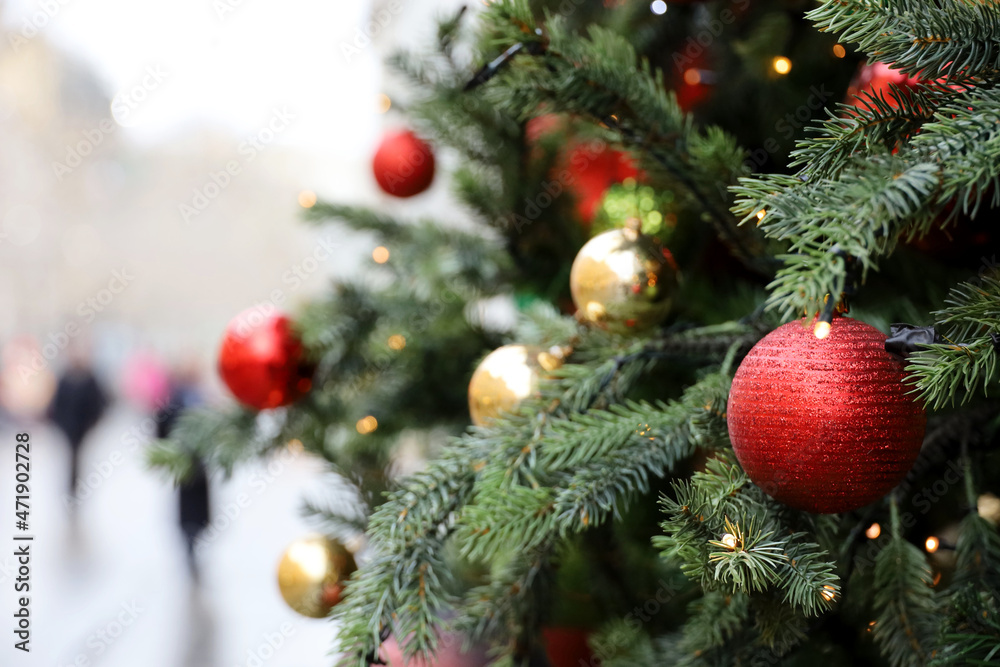 New Year decorations on a city street. Christmas tree with red and golden toy balls on blurred people background New Year decorations on a city street. Christmas tree with red and golden toy balls on blurred people background