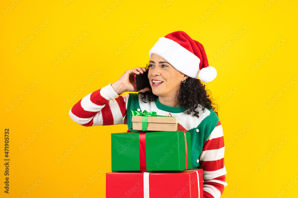 Portrait of adult latin woman calling by mobile phone in a christmas concept on yellow background in Mexico Latin America Portrait of adult latin woman calling by mobile phone in a christmas concept on yellow background in Mexico Latin America