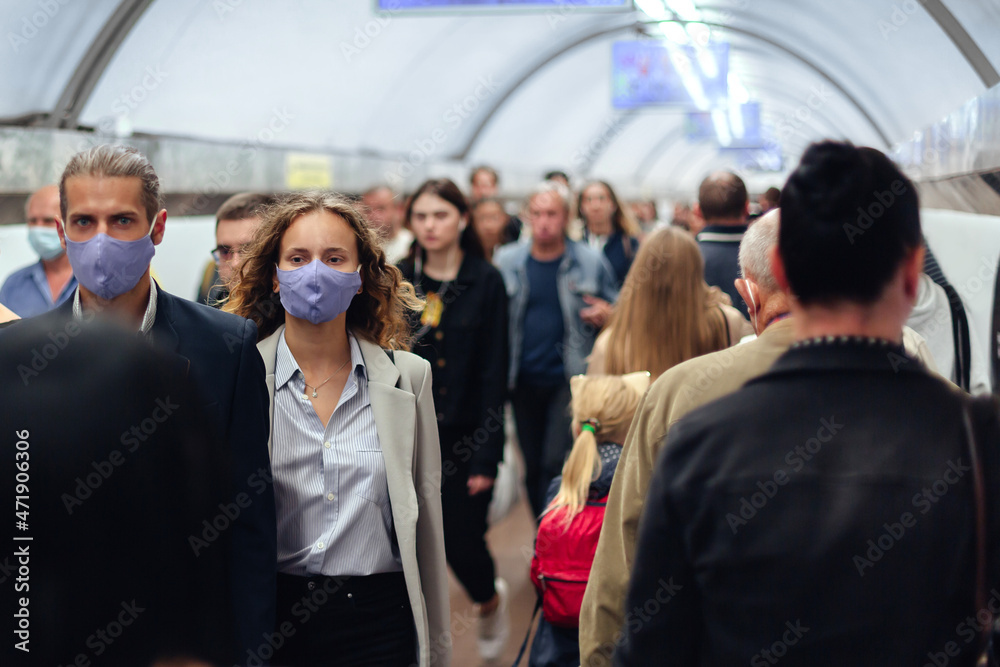 couple in protective masks among the passengers in the subway crossing.