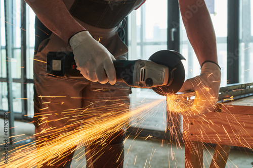 Constructiion work. Worker use angle grinder for metal cutting with sparks photo