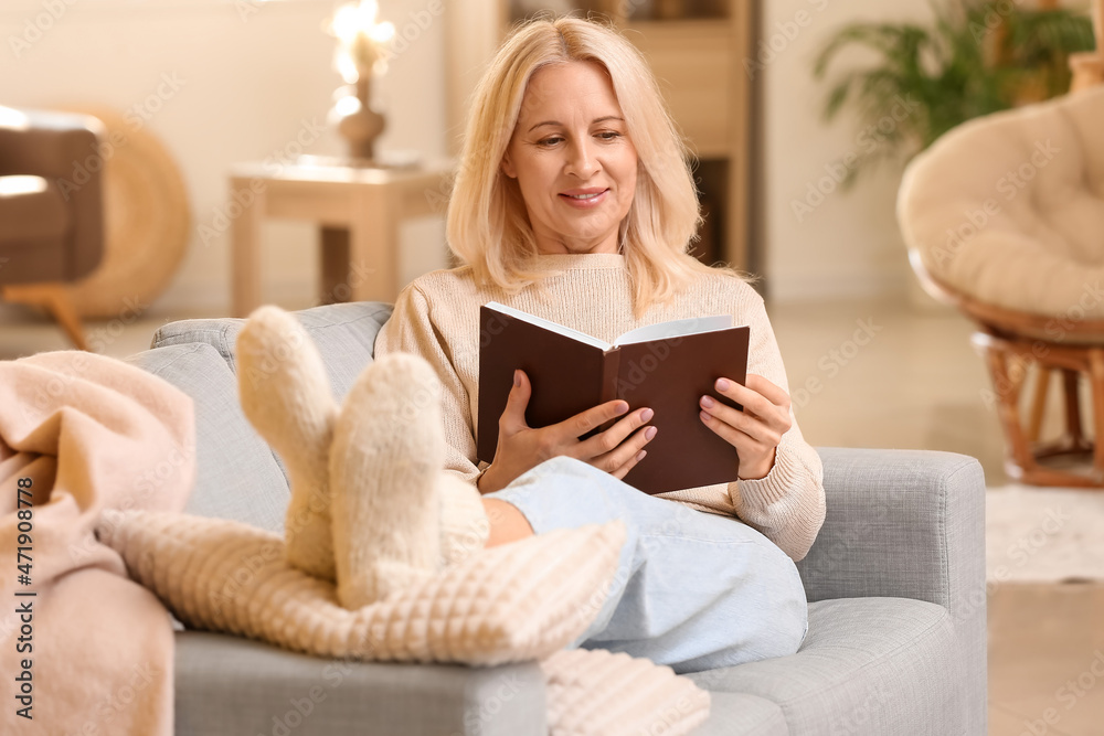 Beautiful mature woman reading book at home on autumn day Beautiful mature woman reading book at home on autumn day