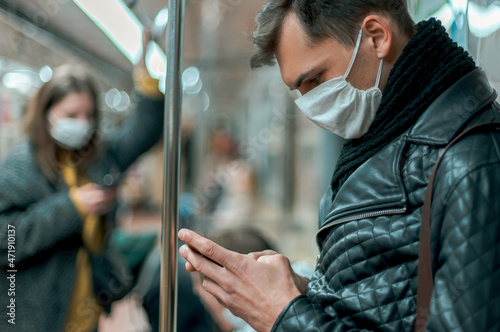passenger in a protective mask reading a message on his smartphone. © yurolaitsalbert