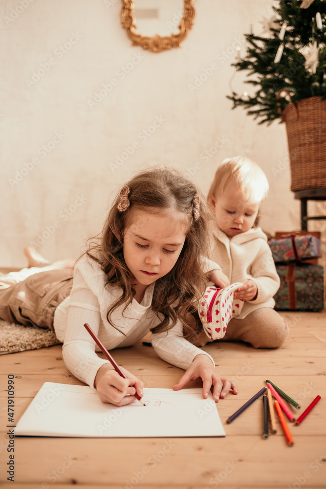 two little sisters are lying on the floor and drawing on paper