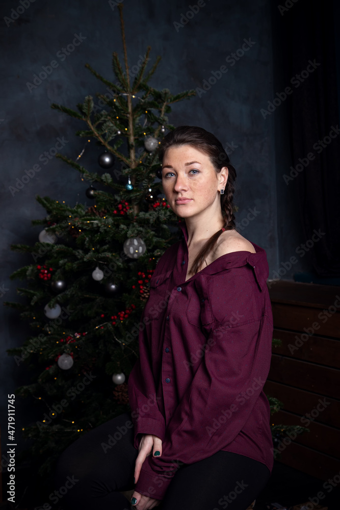 Woman in pajamas near Christmas tree and gifts. Dark blue concept Woman in pajamas near Christmas tree and gifts. Dark blue concept