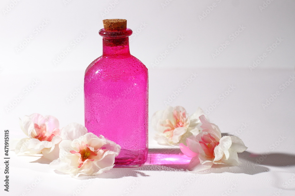 Pink glass bottle with flowers, cosmetic container with reflection