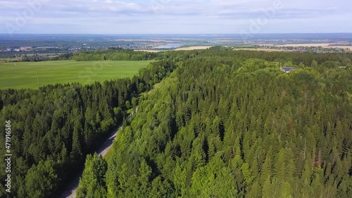 Wonderful landscape view from a bird's-eye view. Clip. A summer green forest with a road for cars next to the field and in the background a small provincial town with fields and small houses photo