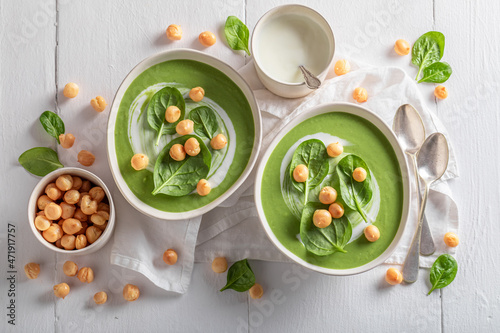Creamy spinach soup with peas puff, leaves and cream.