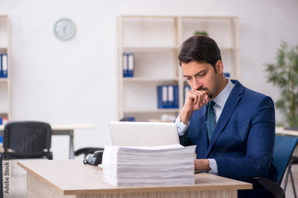 Young male employee and too much work in the office Young male employee and too much work in the office