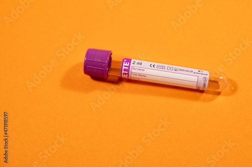 vacuum EDTA blood collection tube with purple cap on orange background, general blood analysis photo