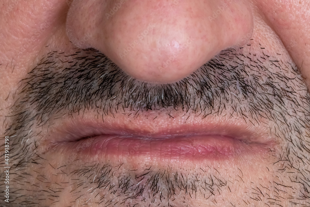 Scornfully clenched lips on an unshaven man's face, close-up. An angry man's mouth. Displeased male face with disgust or arrogance emotion. Negative emotion on caucasian man's face Scornfully clenched lips on an unshaven man's face, close-up. An angry man's mouth. Displeased male face with disgust or arrogance emotion. Negative emotion on caucasian man's face