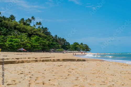 linda praia com areias escuras  ondas  c  u azul e coqueiros 