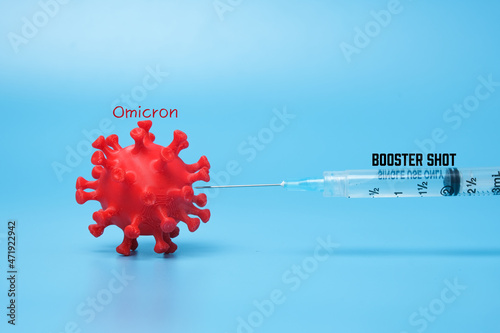 A picture of 3D printed coronavirus with omicron variant word, vaccine and booster shot word. Booster shot helps to fight new variant. photo