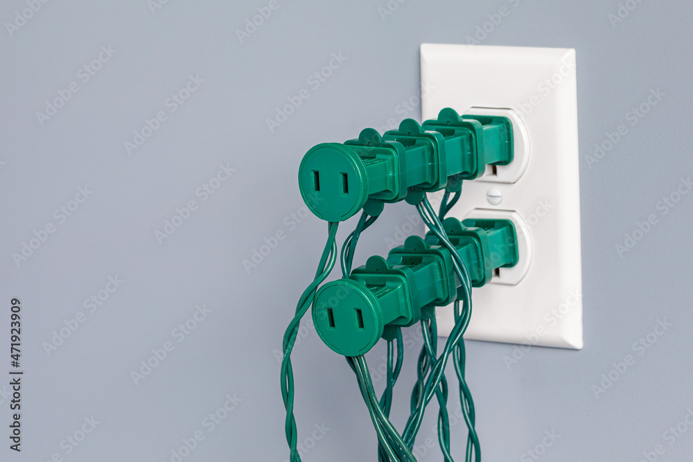Electrical outlet overloaded with Christmas string lights. Holiday